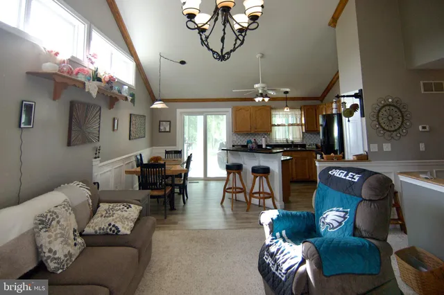 a living room with furniture kitchen view and a chandelier