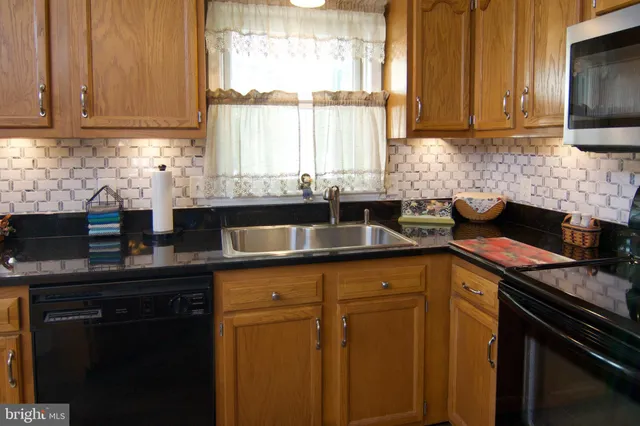 a kitchen with stainless steel appliances granite countertop a sink a stove and a microwave
