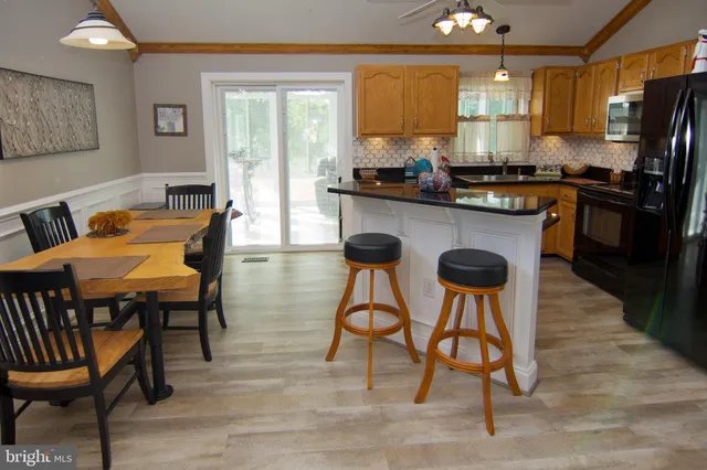 a kitchen with stainless steel appliances kitchen island a table chairs in it and wooden floors