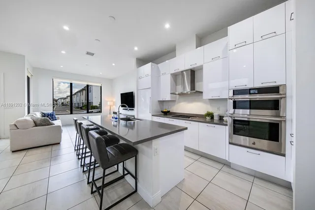 a kitchen with stainless steel appliances kitchen island granite countertop a stove a sink a refrigerator and white cabinets