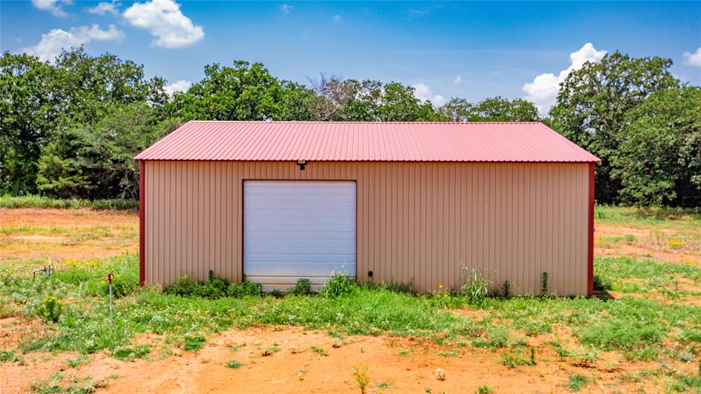 1789 Brumelow Road Whitesboro, TX 76273 - Photo 18 of 30 Metal utility building featuring a corrugated red roof, tan siding, and a white roll-up door