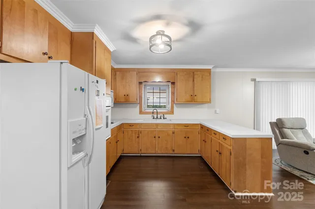 a large white kitchen with a stove a refrigerator and dishwasher with wooden floor