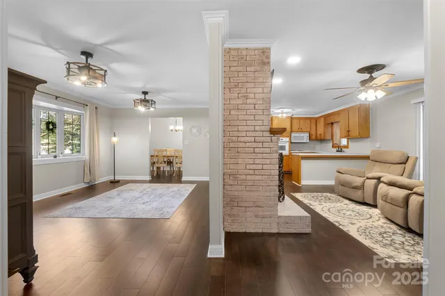 an open kitchen with granite countertop a refrigerator stove top oven and couches with wooden floor