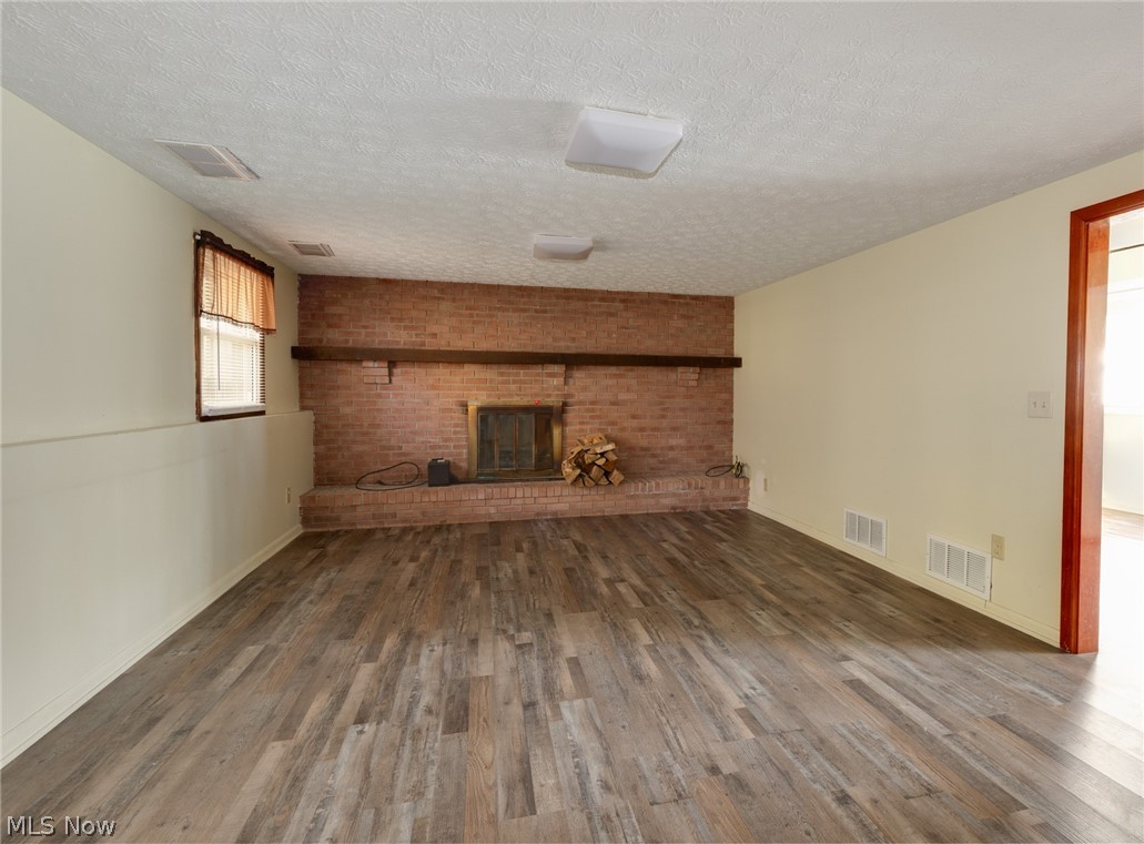 9416 Kieffer Road Mantua, OH 44255 - Photo 17 of 29 Family room with a textured ceiling, a brick fireplace, and wood style floors
