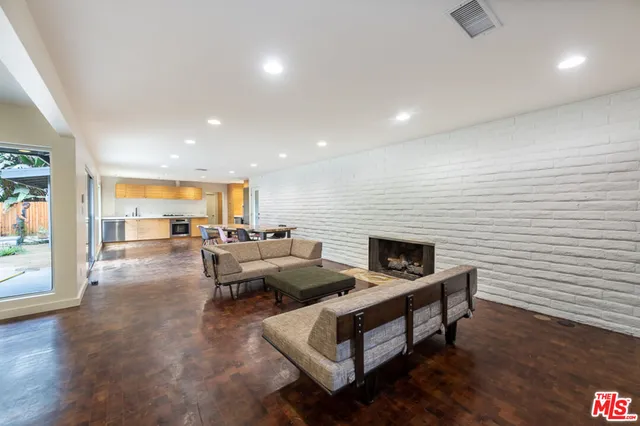 a living room with couches chairs and kitchen view with wooden floor