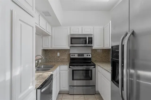 a kitchen with stainless steel appliances granite countertop a refrigerator and a stove