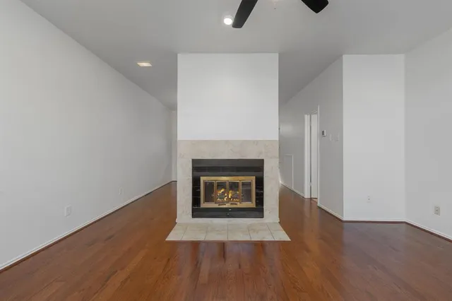 an empty room with wooden floor fan and windows