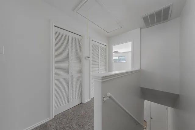 an empty room with wooden floor a ceiling fan a fireplace and entryway