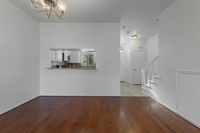 a view of a livingroom with wooden floor and a kitchen space