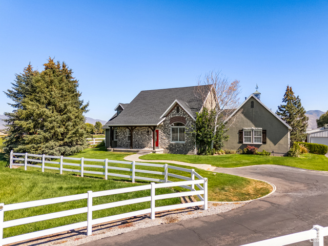 9337 South 3950th Street West Payson, UT 84651 - Photo 1 of 1 View of front of house with covered porch, a fenced front yard, a shingled roof, and stone siding