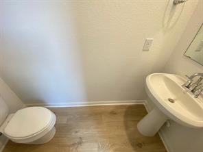 213 Saide Street Georgetown, TX 78626 - Photo 15 of 32 Bathroom featuring a pedestal sink with chrome fixtures, a toilet, wood-finish flooring, and white baseboards