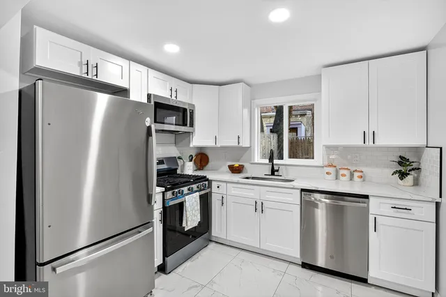 a kitchen with white cabinets and stainless steel appliances
