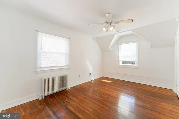 an empty room with wooden floor chandelier fan and windows