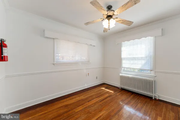 an empty room with wooden floor chandelier fan and windows