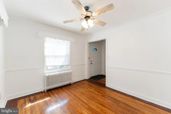 an empty room with wooden floor chandelier fan and windows
