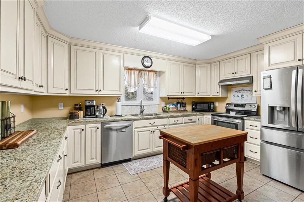 11 Paige Street Cartersville, GA 30121 - Photo 14 of 49 a kitchen with stainless steel appliances granite countertop a stove top oven a sink dishwasher and a refrigerator with wooden cabinets