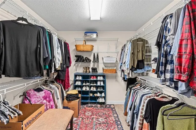 a view of walk in closet with clothes and shoes