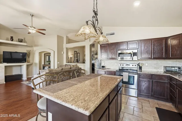 a kitchen with granite countertop a stove a sink a kitchen island with cabinets and wooden floor