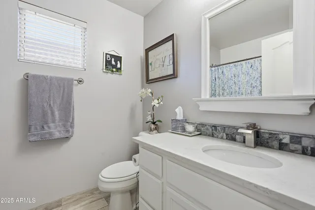 a bathroom with a granite countertop toilet sink and a mirror