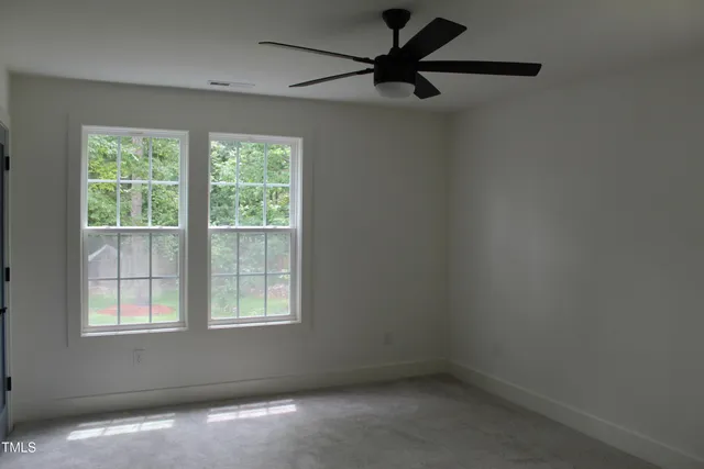 an empty room with a window and a fan