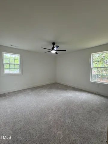 an empty room with windows and ceiling fan view