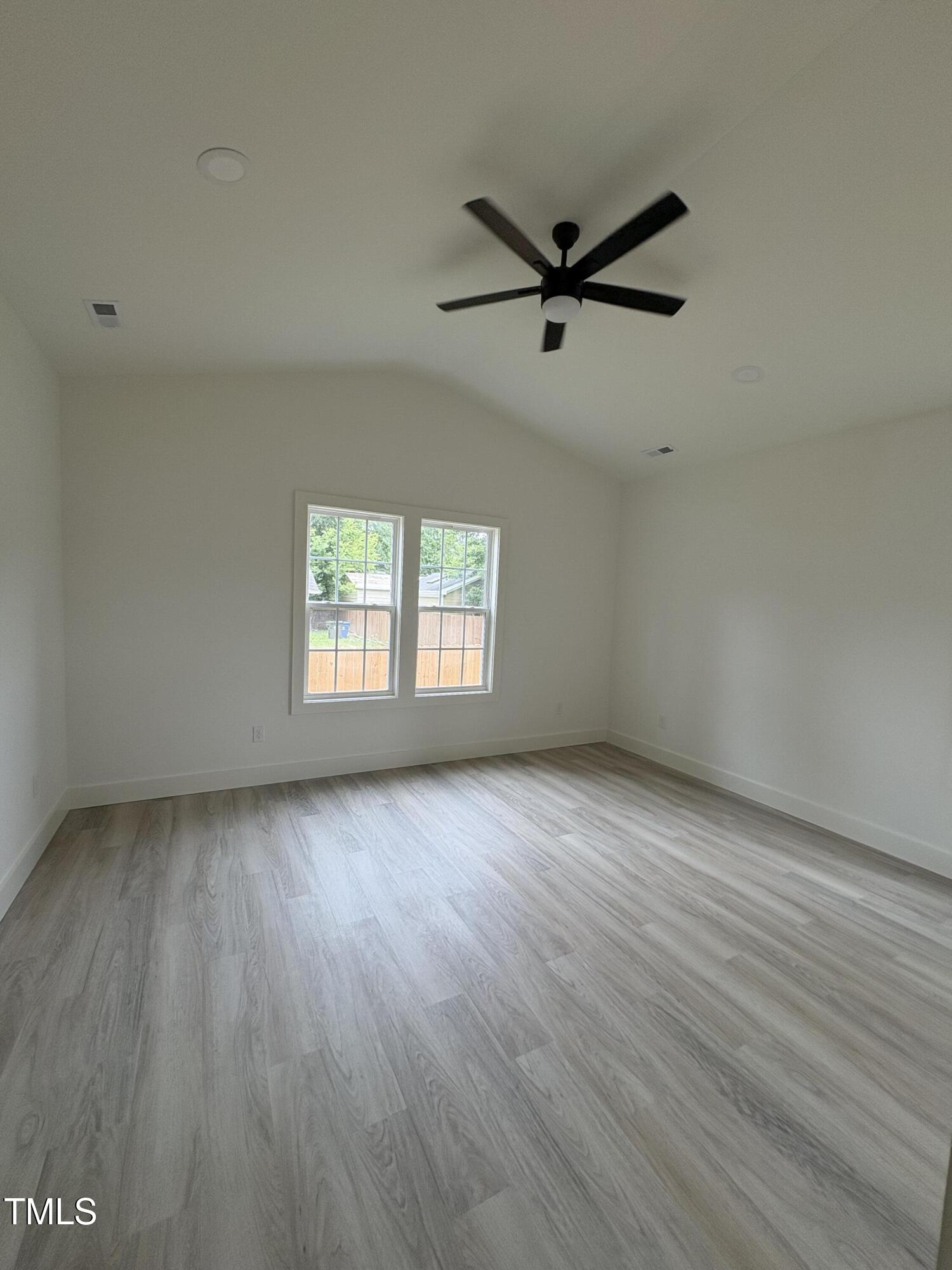 4511 Denfield Street Durham, NC 27704 - Photo 9 of 40 an empty room with wooden floor a ceiling fan and windows