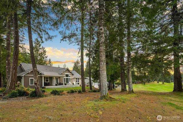 a view of a big house with a big yard and large trees