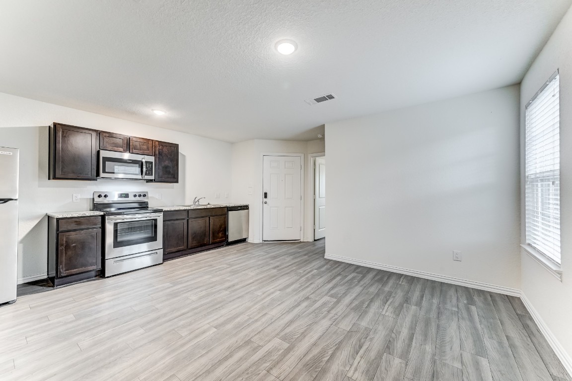 7925 Way Street, Unit A Houston, TX 77028 - Photo 6 of 29 a large kitchen with a stove top oven a sink dishwasher a microwave oven and a refrigerator with wooden floor