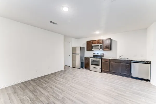 a large kitchen with a wooden floor and stainless steel appliances