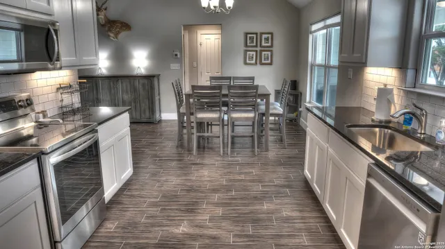 a kitchen with granite countertop a sink a counter top space and stainless steel appliances