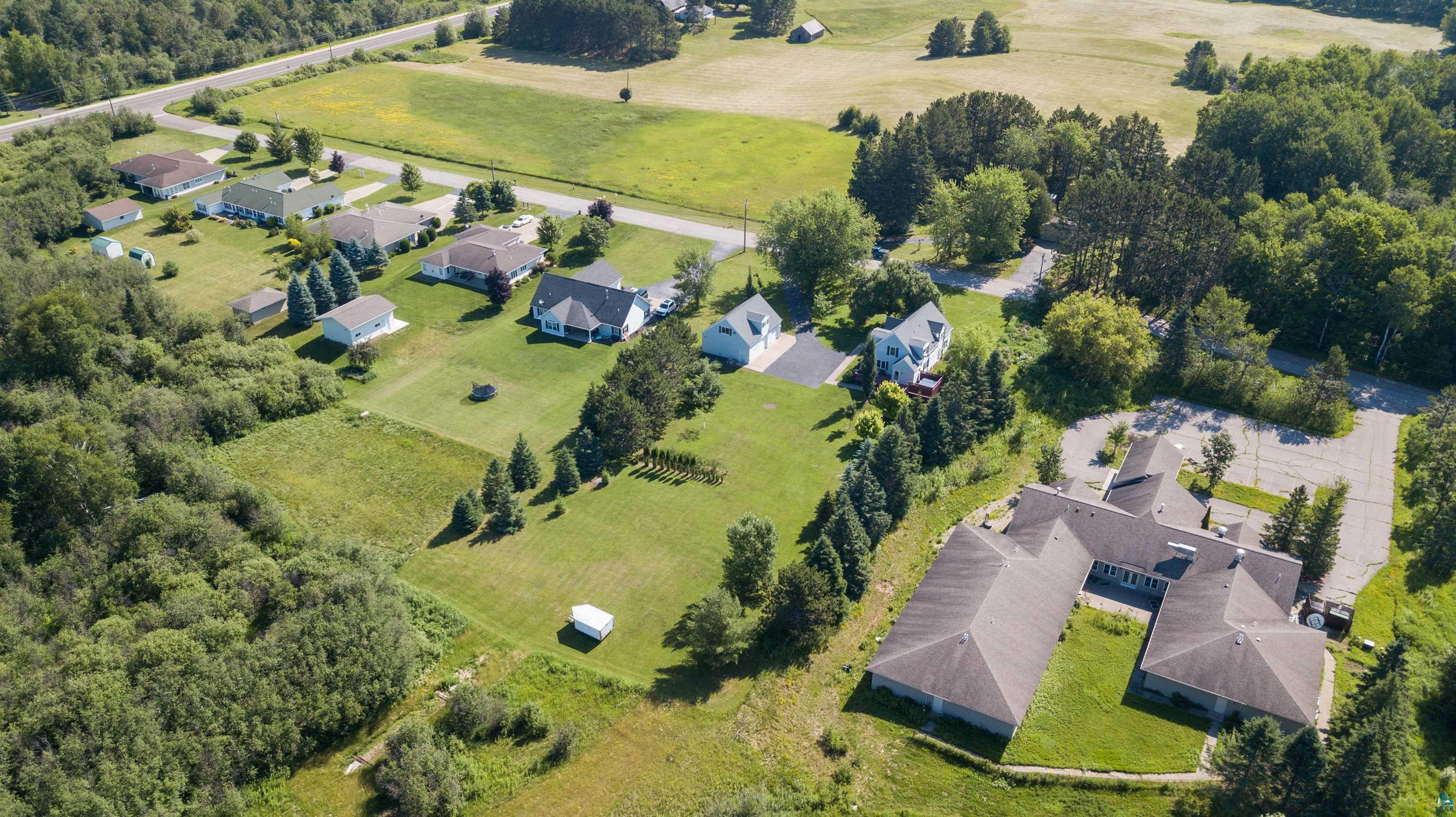 4073 Reinke Road Duluth, MN 55811 - Photo 28 of 32 Expansive property featuring a large U-shaped building with ample parking, surrounded by mature trees and verdant lawns