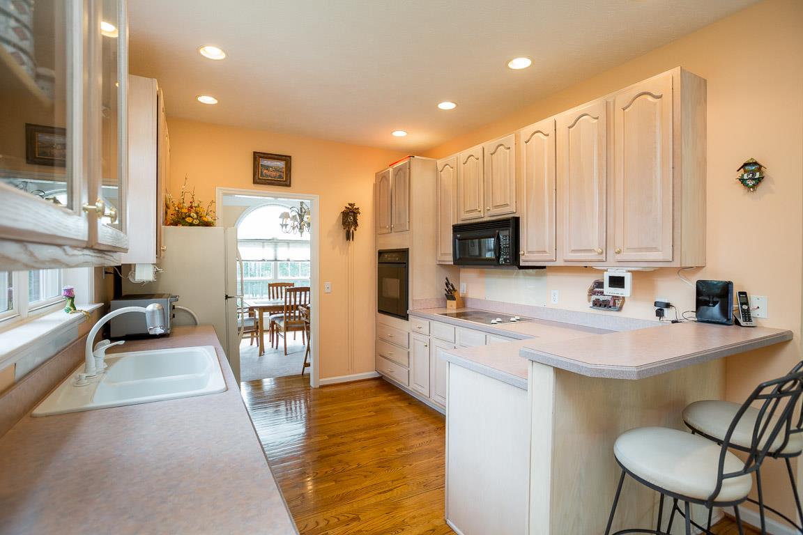 1066 Harkreader Road Mount Juliet, TN 37122 - Photo 18 of 30 a kitchen with stainless steel appliances a sink a stove a refrigerator cabinets and a dining table with wooden floor