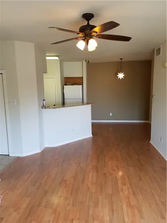 a view of a room with wooden floor and ceiling fan