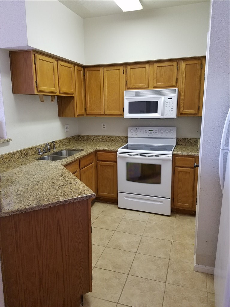2450 Wickersham Lane, Unit 1317 Austin, TX 78741 - Photo 5 of 20 a kitchen with stainless steel appliances granite countertop a stove a sink and a microwave