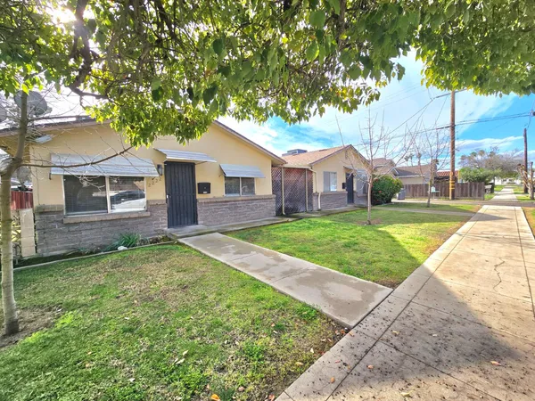 a view of a house with a yard and large tree