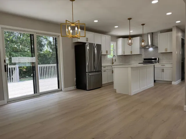 a kitchen with refrigerator a stove a sink and a large window