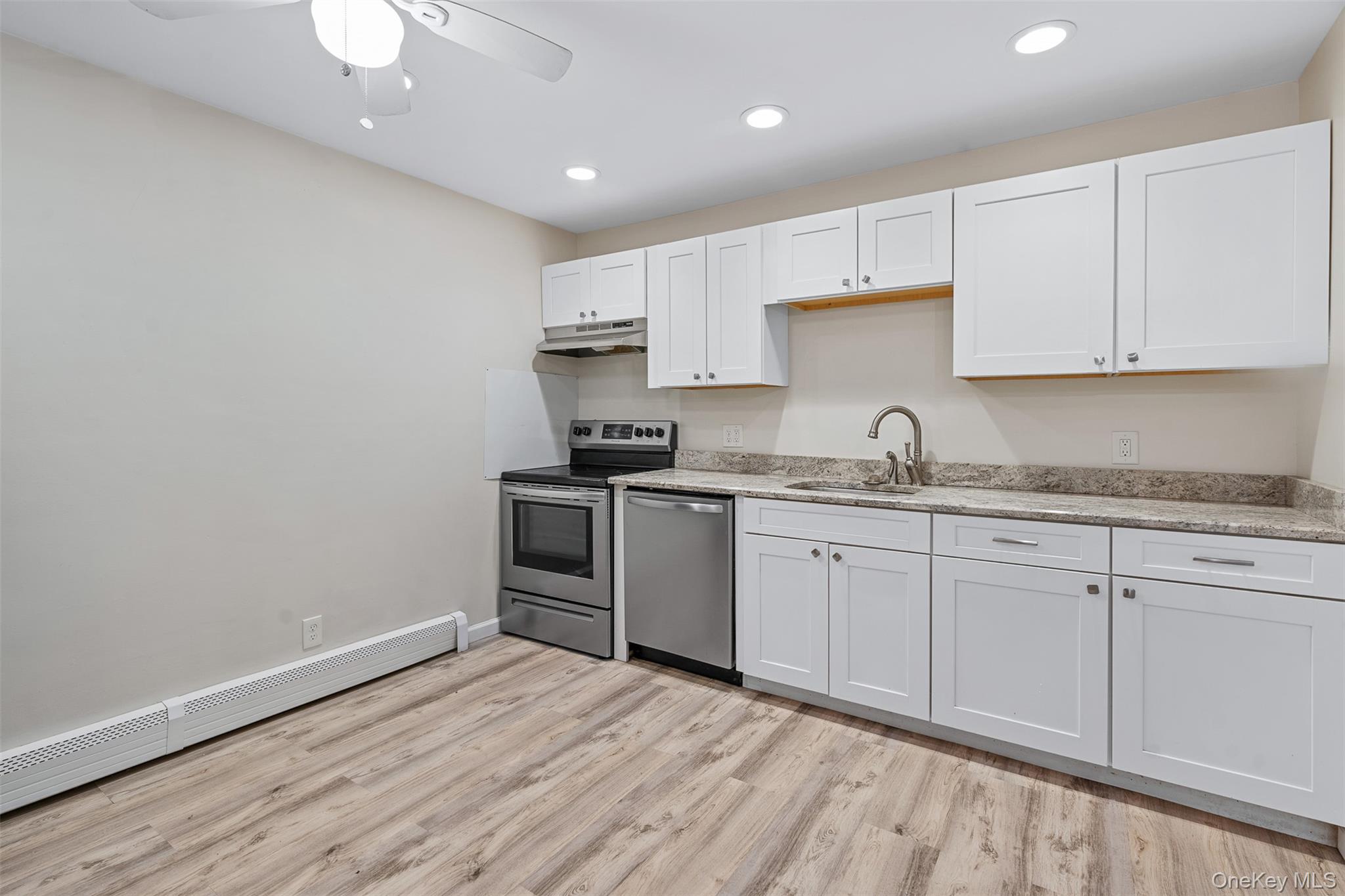 68 Gerald Drive, Unit D1 Poughkeepsie, NY 12601 - Photo 11 of 29 Kitchen with stainless steel appliances, under cabinet range hood, a baseboard radiator, light wood-style flooring, and a ceiling fan
