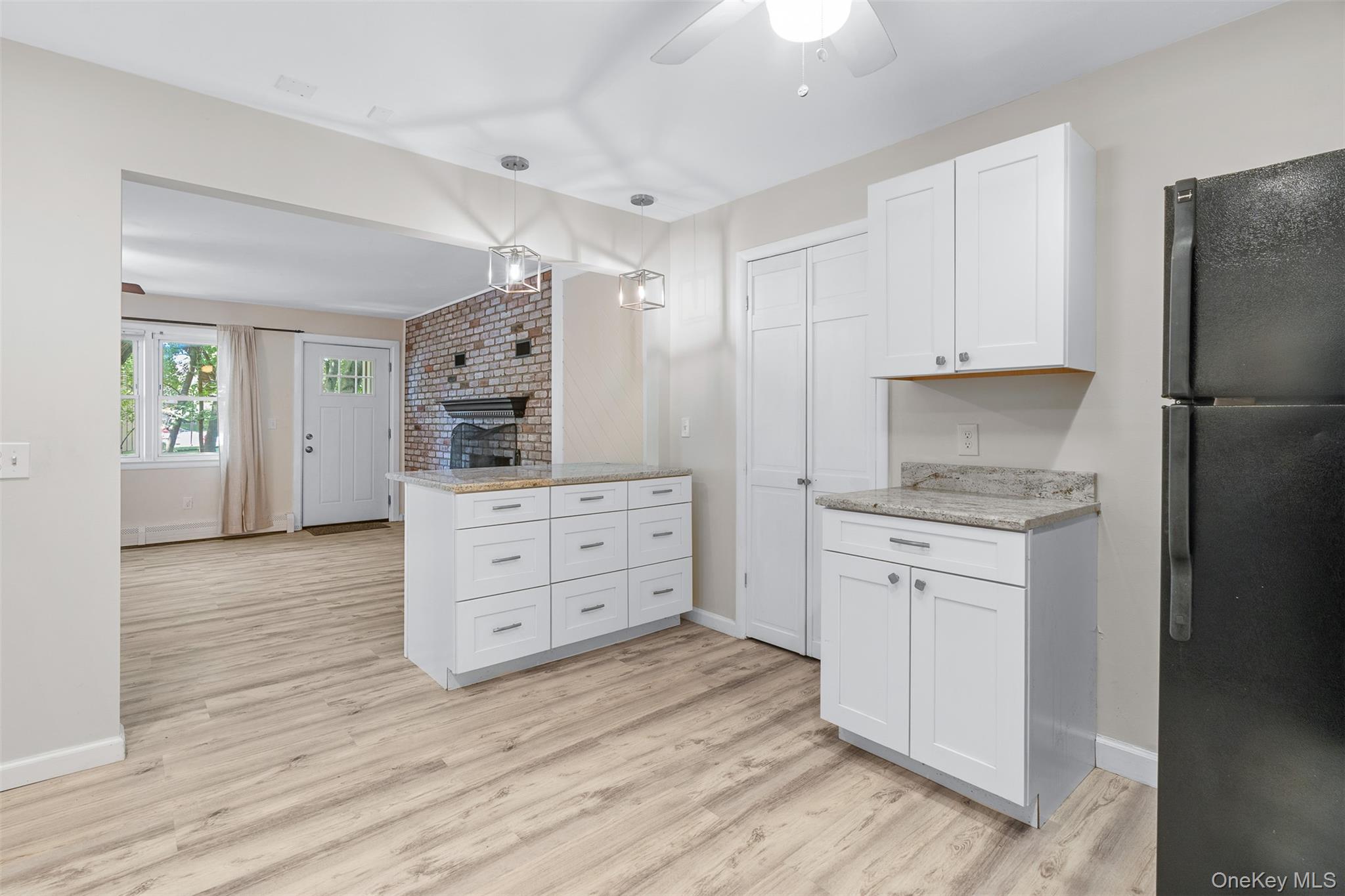 68 Gerald Drive, Unit D1 Poughkeepsie, NY 12601 - Photo 12 of 29 Kitchen with freestanding refrigerator, ceiling fan, white cabinets, light wood finished floors, and a fireplace
