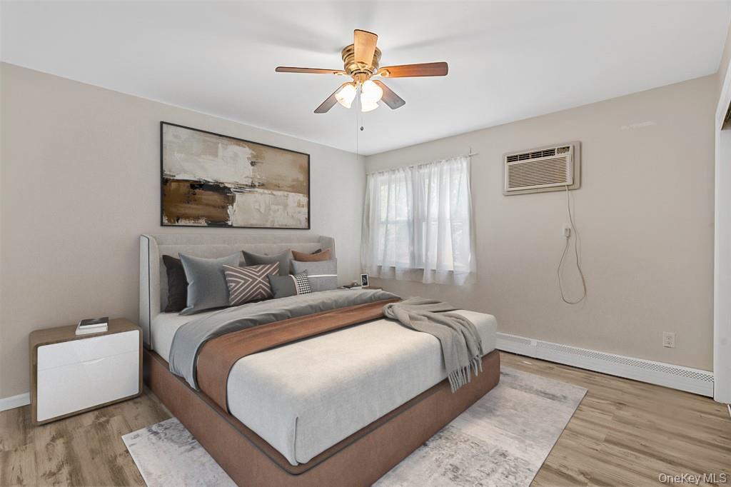 68 Gerald Drive, Unit D1 Poughkeepsie, NY 12601 - Photo 17 of 29 Bedroom featuring wood finished floors, baseboard heating, ceiling fan, and a wall unit AC