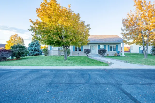 a view of a house next to a big yard and large trees