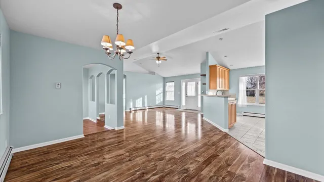 a view of a room with wooden floor chandelier and windows