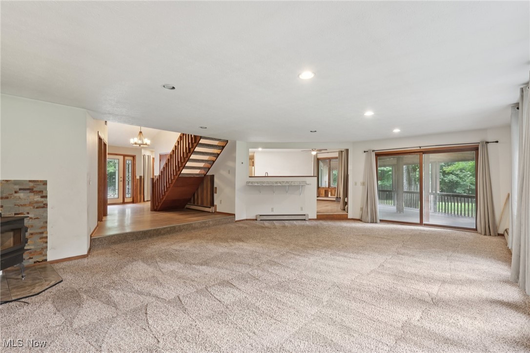 5643 Chapin Road Madison, OH 44057 - Photo 9 of 50 Unfurnished living room with baseboard heating, carpet, stairs, a wood stove, and recessed lighting