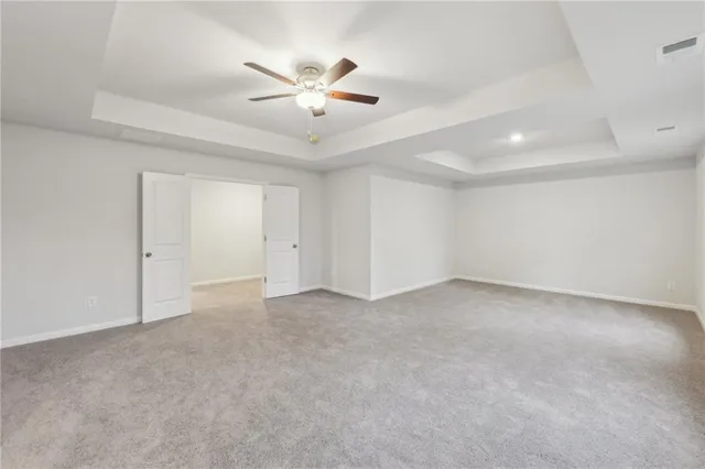 an empty room with chandelier fan and windows