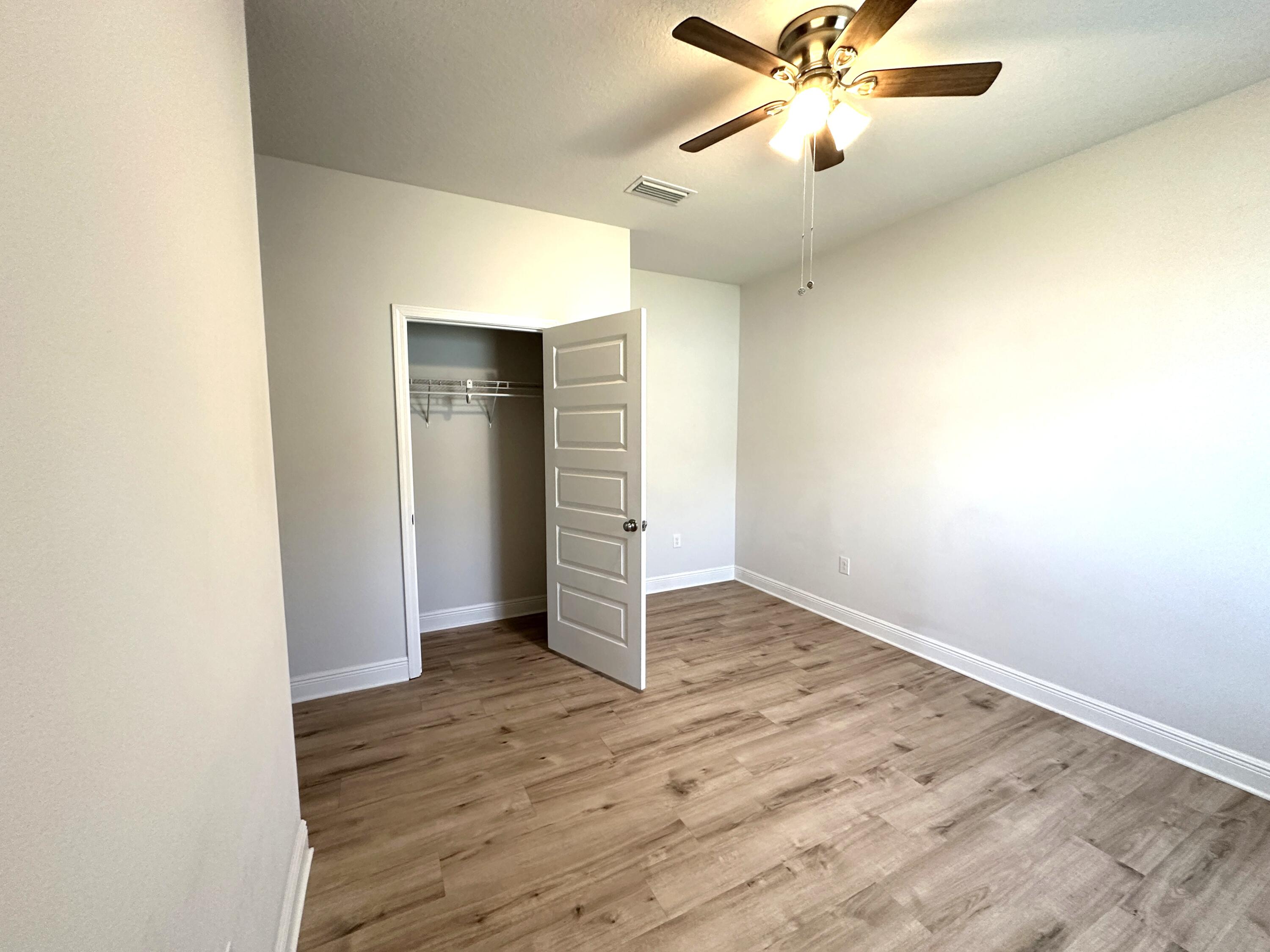 56 Secluded Circle Freeport, FL 32439 - Photo 11 of 26 an empty room with a ceiling fan and wooden floor