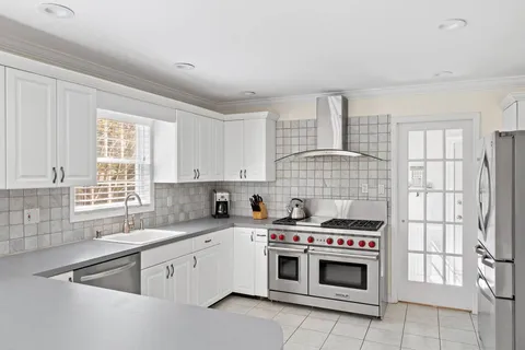 a kitchen with stainless steel appliances a stove a sink and white cabinets