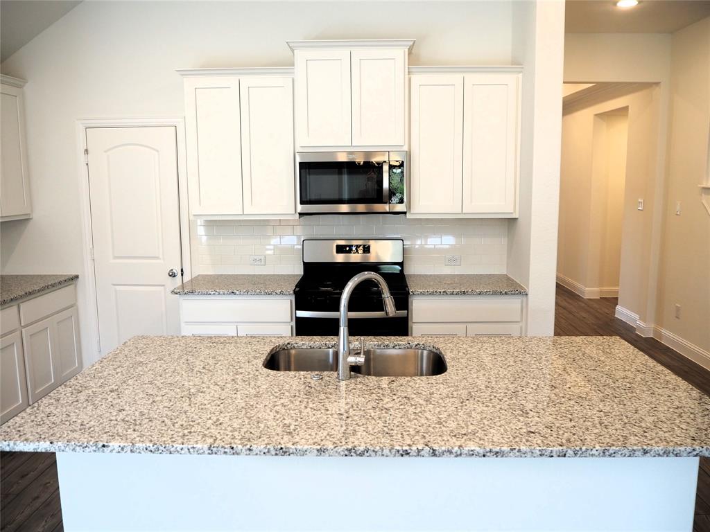2201 Yellowhammer Road Denton, TX 76205 - Photo 7 of 36 a kitchen with kitchen island granite countertop a sink a stove and a microwave