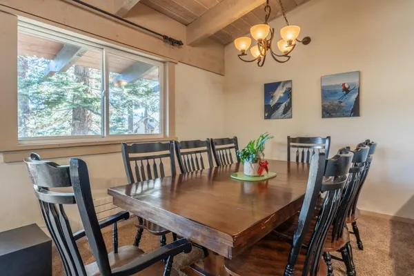 a view of a dining room with furniture a chandelier and large windows