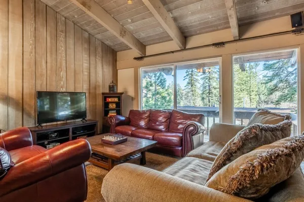 a living room with furniture a flat screen tv and a floor to ceiling window