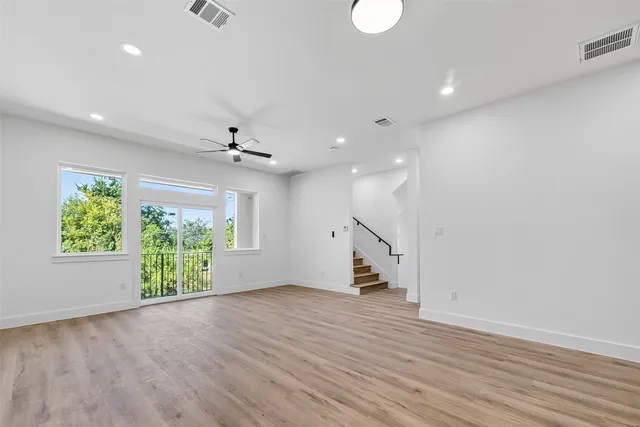 an empty room with wooden floor gym equipment and windows