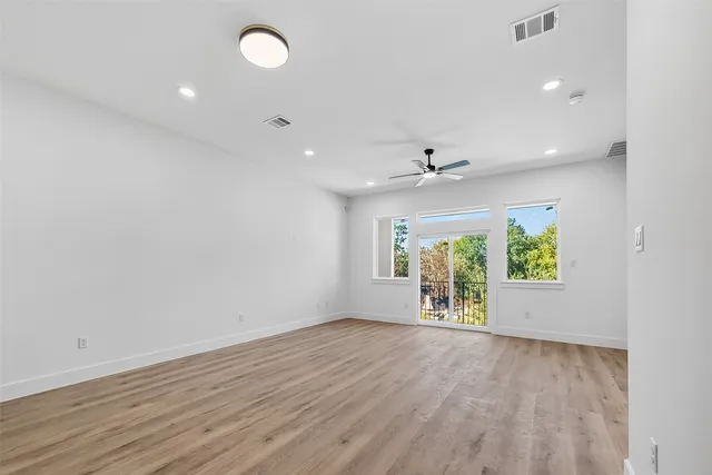 an empty room with windows and ceiling fan